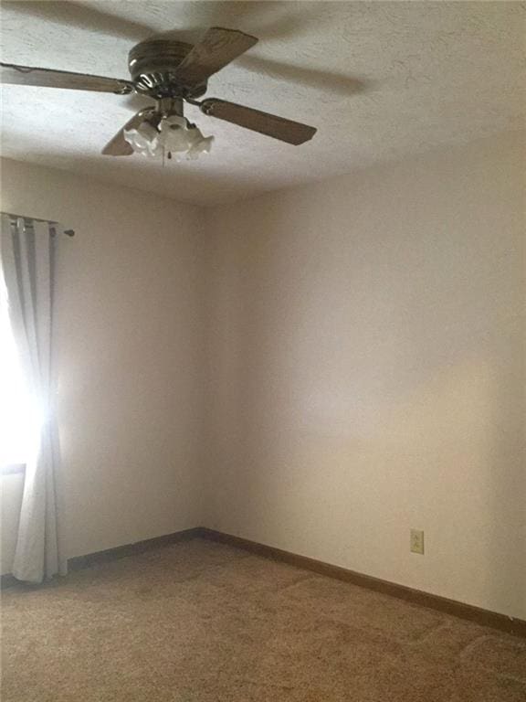 carpeted empty room with ceiling fan and a textured ceiling