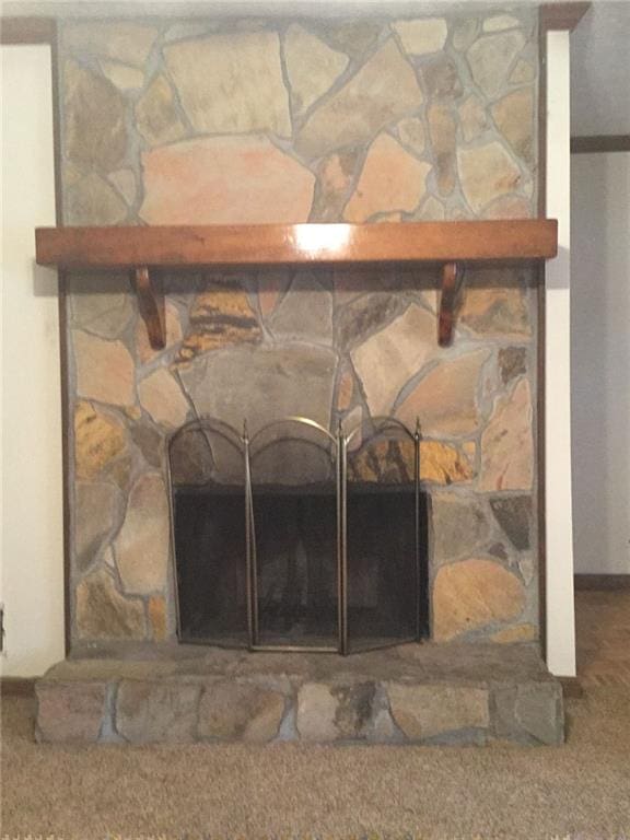 interior details featuring carpet and a stone fireplace