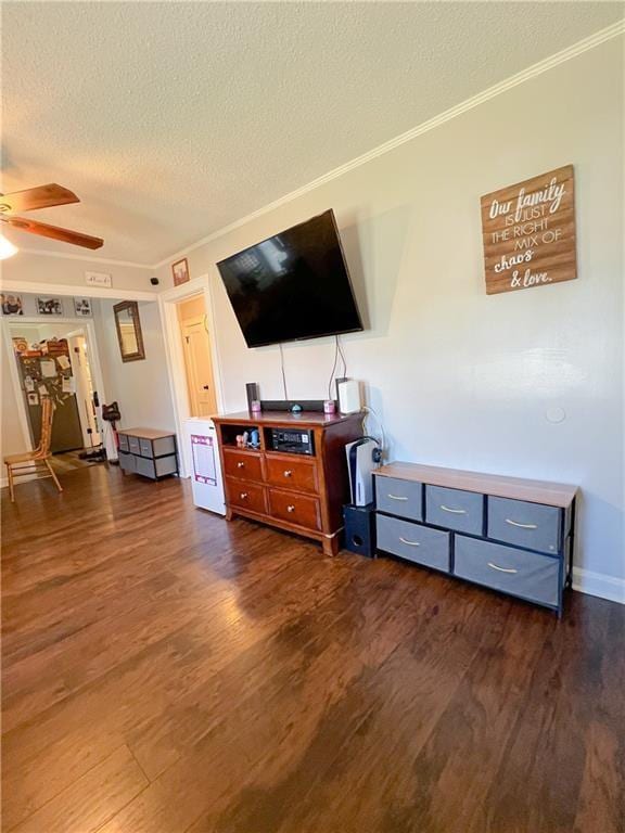 living room featuring ceiling fan, ornamental molding, dark hardwood / wood-style floors, and a textured ceiling