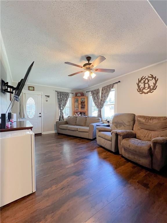 living room featuring dark wood-type flooring, ceiling fan, ornamental molding, and a textured ceiling