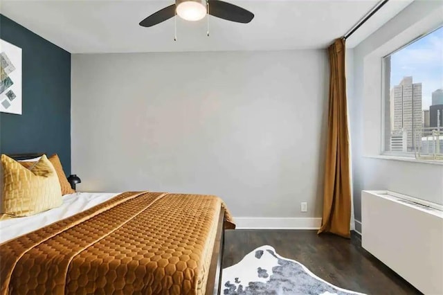 bedroom with ceiling fan, radiator heating unit, and dark hardwood / wood-style flooring