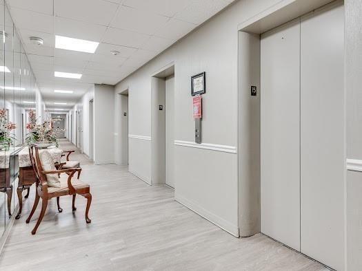 corridor featuring elevator, a drop ceiling, and light hardwood / wood-style flooring