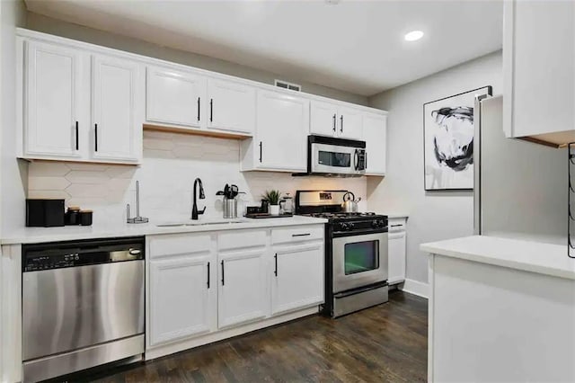 kitchen featuring sink, appliances with stainless steel finishes, backsplash, dark hardwood / wood-style floors, and white cabinets