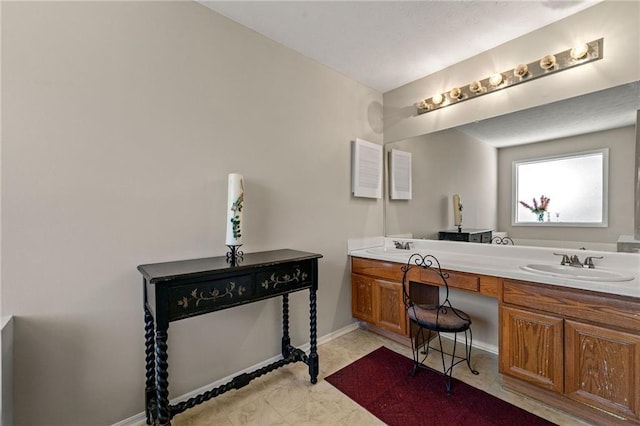 bathroom with double vanity, a sink, and baseboards