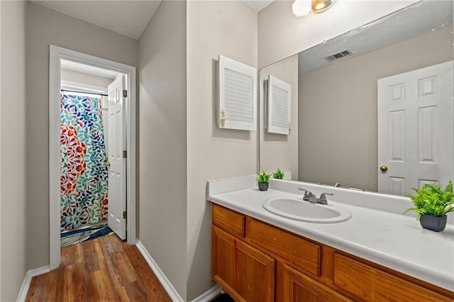 bathroom featuring wood finished floors, vanity, visible vents, and baseboards