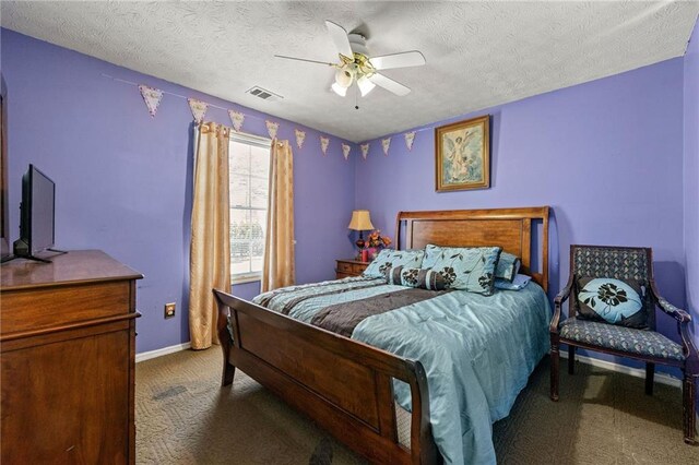 bedroom featuring baseboards, visible vents, a ceiling fan, a textured ceiling, and dark carpet