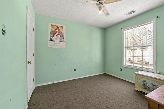 unfurnished bedroom featuring dark colored carpet, visible vents, a textured ceiling, and baseboards