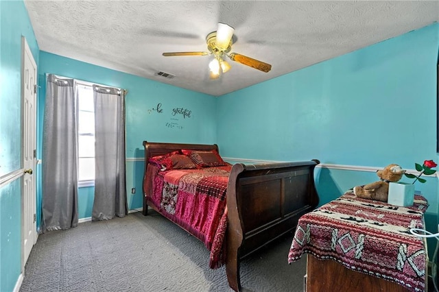 carpeted bedroom featuring baseboards, a textured ceiling, visible vents, and a ceiling fan