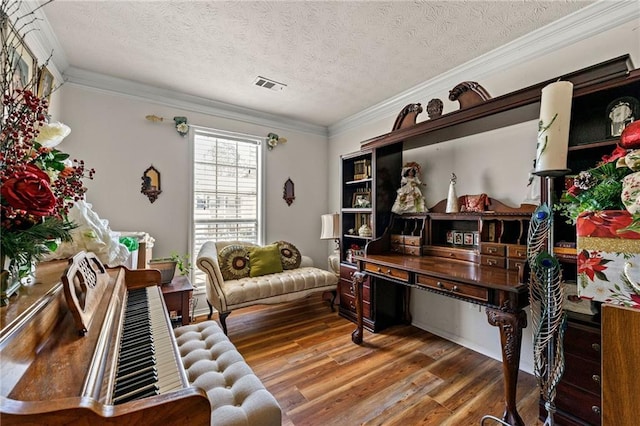 sitting room with ornamental molding, visible vents, a textured ceiling, and wood finished floors