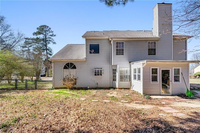 back of house with a chimney and fence