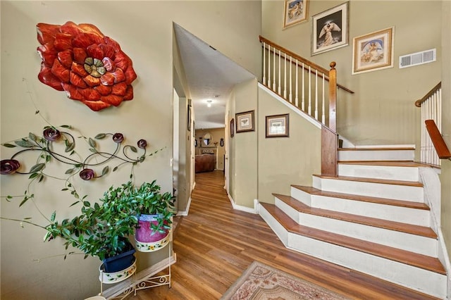 stairway with wood finished floors, visible vents, and baseboards