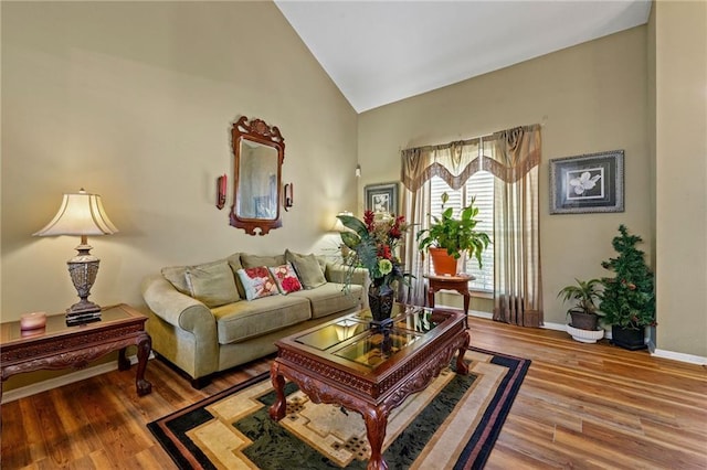 living room with high vaulted ceiling, baseboards, and wood finished floors