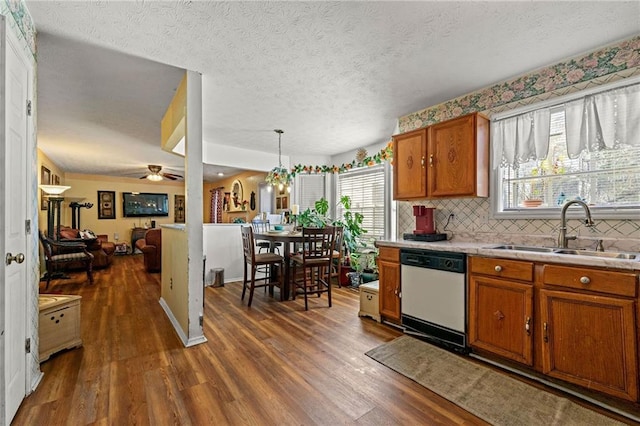 kitchen featuring pendant lighting, light countertops, open floor plan, white dishwasher, and a sink