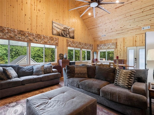 living room featuring high vaulted ceiling, ceiling fan, french doors, wooden walls, and dark hardwood / wood-style flooring