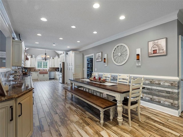 dining area with crown molding, light hardwood / wood-style flooring, a textured ceiling, and a chandelier