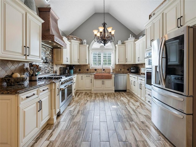 kitchen featuring an inviting chandelier, appliances with stainless steel finishes, custom exhaust hood, backsplash, and hanging light fixtures