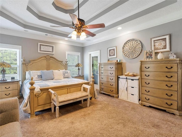 carpeted bedroom featuring ceiling fan, crown molding, a tray ceiling, and a textured ceiling