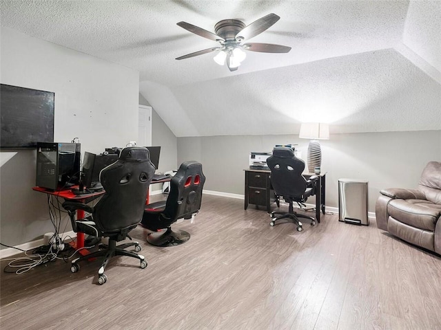 office space with ceiling fan, a textured ceiling, light hardwood / wood-style flooring, and vaulted ceiling