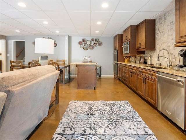 kitchen featuring appliances with stainless steel finishes, tasteful backsplash, light stone counters, a breakfast bar area, and a paneled ceiling