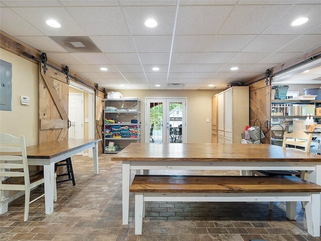 kitchen with wood counters, a barn door, french doors, a paneled ceiling, and dark tile flooring