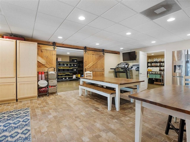 dining space featuring a barn door and a drop ceiling