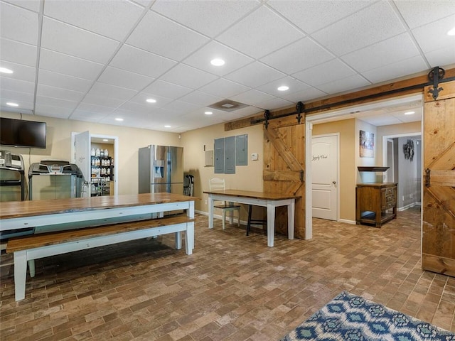 interior space featuring a barn door and a drop ceiling