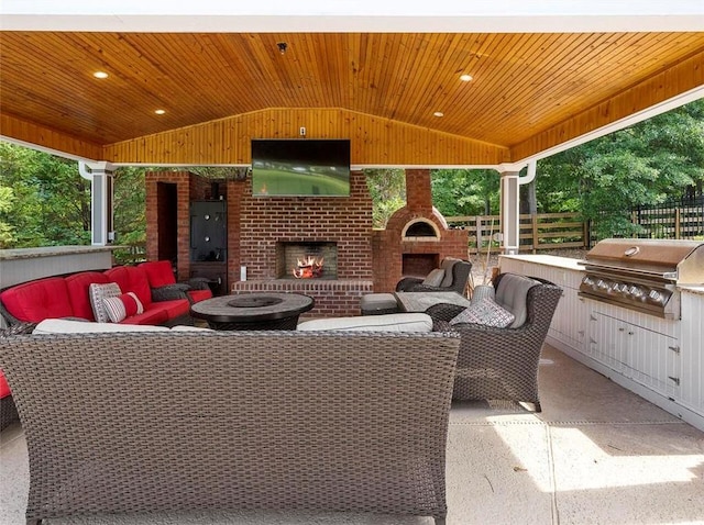 view of patio featuring grilling area, an outdoor living space with a fireplace, and exterior kitchen