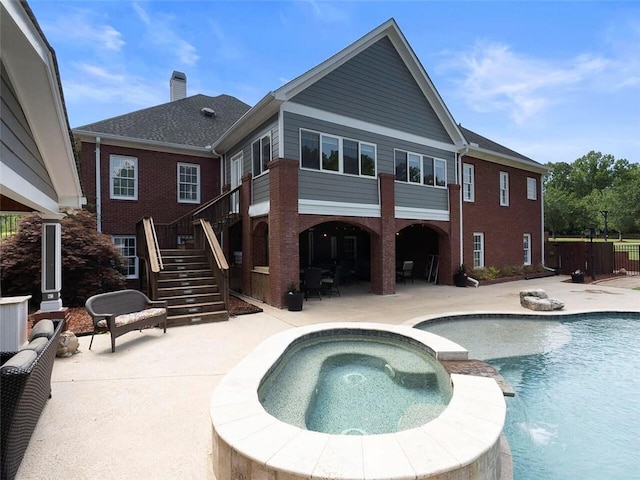 rear view of property featuring a patio area, pool water feature, and a swimming pool with hot tub