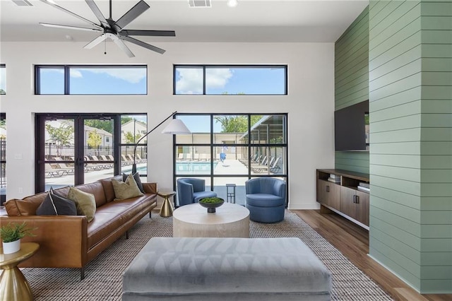 living room with wood-type flooring, a towering ceiling, ceiling fan, and french doors