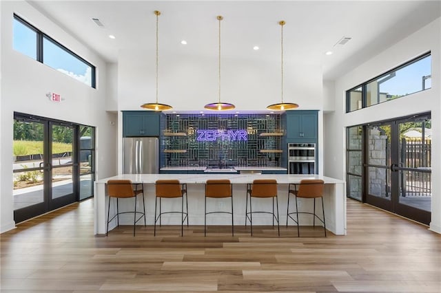 kitchen featuring pendant lighting, a breakfast bar area, stainless steel appliances, blue cabinets, and french doors