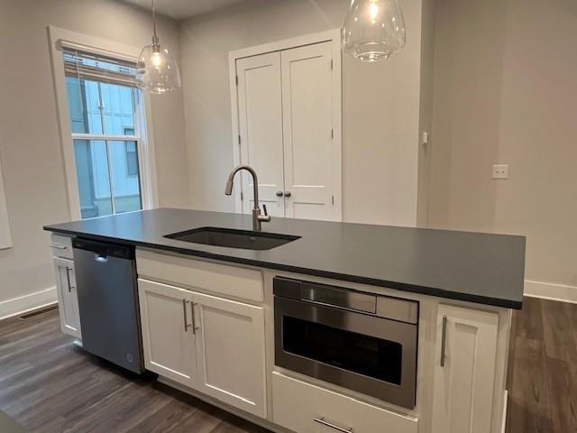 kitchen featuring sink, white cabinets, hanging light fixtures, a kitchen island with sink, and stainless steel appliances