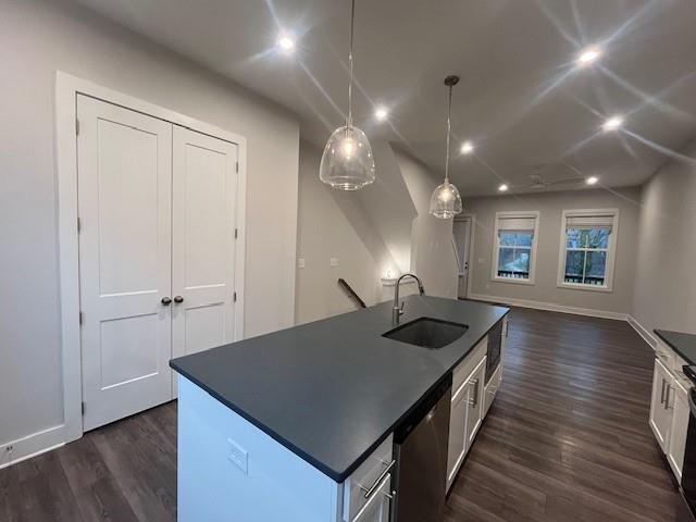 kitchen with sink, stainless steel dishwasher, an island with sink, pendant lighting, and white cabinets