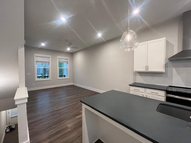 kitchen with white cabinetry, dark hardwood / wood-style flooring, hanging light fixtures, ceiling fan, and wall chimney exhaust hood