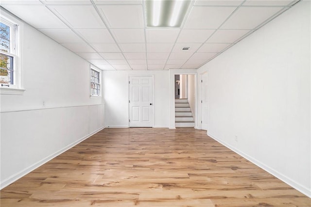 basement featuring a paneled ceiling and light hardwood / wood-style flooring