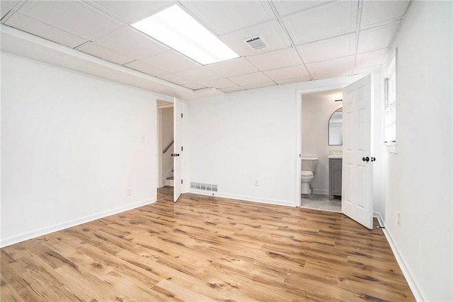 interior space featuring a paneled ceiling and light hardwood / wood-style flooring