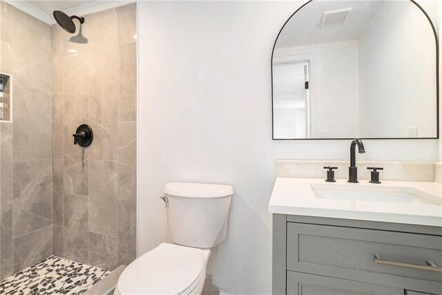 bathroom with tiled shower, vanity, and toilet