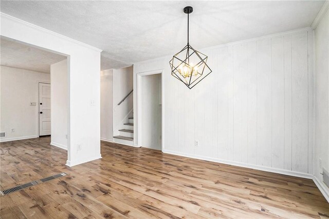 unfurnished room with hardwood / wood-style floors, a textured ceiling, and an inviting chandelier