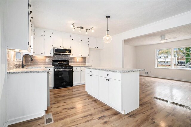 kitchen with sink, decorative light fixtures, a kitchen island, white cabinetry, and black range with gas cooktop