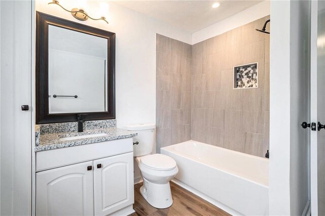 full bathroom featuring hardwood / wood-style flooring, vanity, toilet, and tiled shower / bath