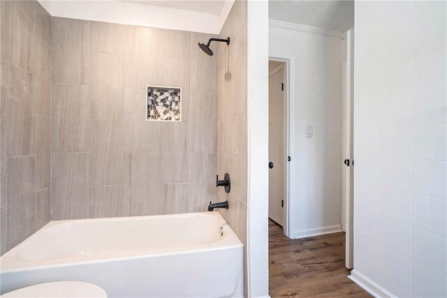 bathroom with hardwood / wood-style floors, tiled shower / bath combo, and toilet