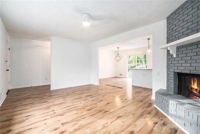 unfurnished living room featuring ceiling fan, hardwood / wood-style floors, and a brick fireplace