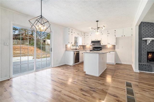 kitchen with decorative light fixtures, light hardwood / wood-style flooring, appliances with stainless steel finishes, a notable chandelier, and white cabinetry