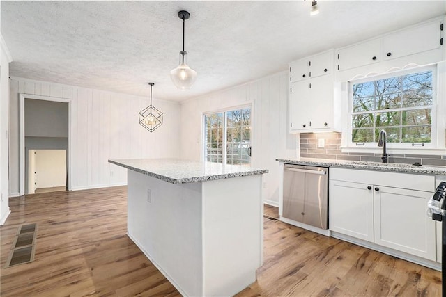 kitchen featuring appliances with stainless steel finishes, sink, pendant lighting, white cabinets, and light hardwood / wood-style floors