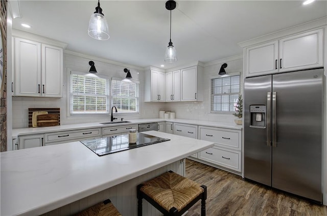 kitchen with stainless steel appliances, white cabinetry, hanging light fixtures, and sink