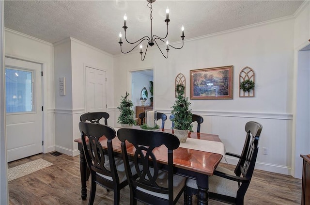 dining area with a notable chandelier, hardwood / wood-style floors, a textured ceiling, and ornamental molding