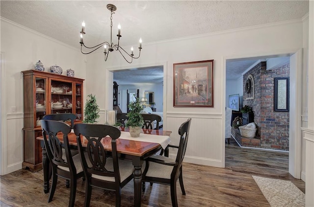 dining room with a textured ceiling, dark hardwood / wood-style flooring, ornamental molding, and brick wall