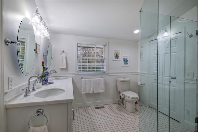 bathroom with a shower with door, vanity, and toilet