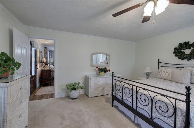 carpeted bedroom with a textured ceiling, ceiling fan, and crown molding