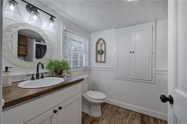 bathroom featuring hardwood / wood-style flooring, vanity, toilet, and a textured ceiling