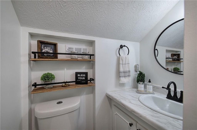 bathroom featuring vanity, a textured ceiling, and toilet